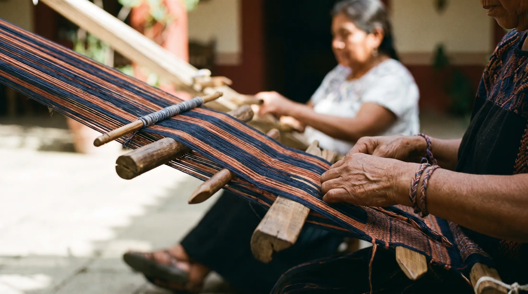 Manos de tejedoras trabajando en un telar de cintura